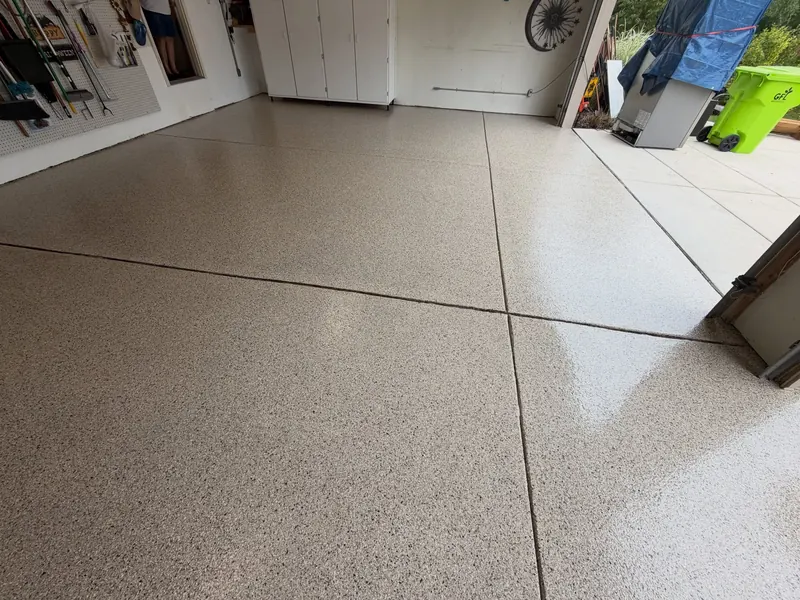 Garage floor with a tan and black flake coating, door open to the driveway